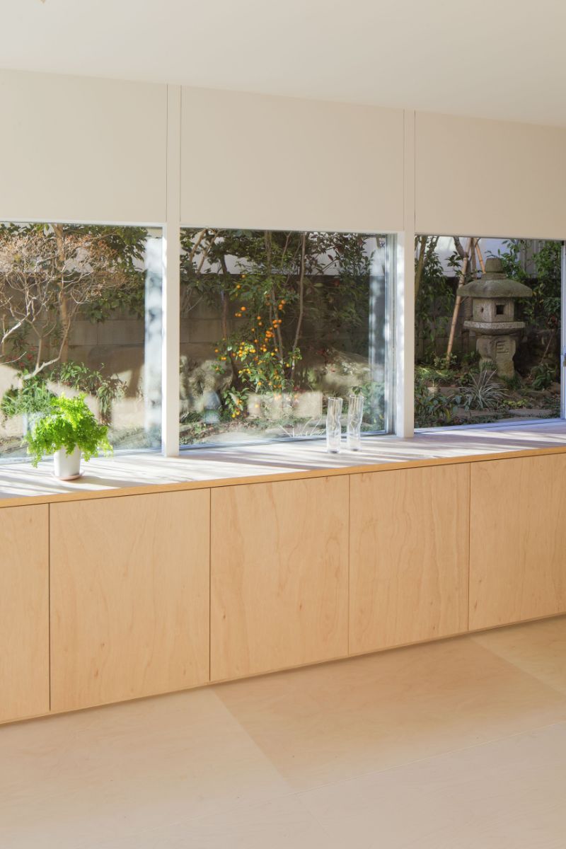 A minimalist kitchen cabinetry with a glass slit providing unobstructed views of the garden outside.