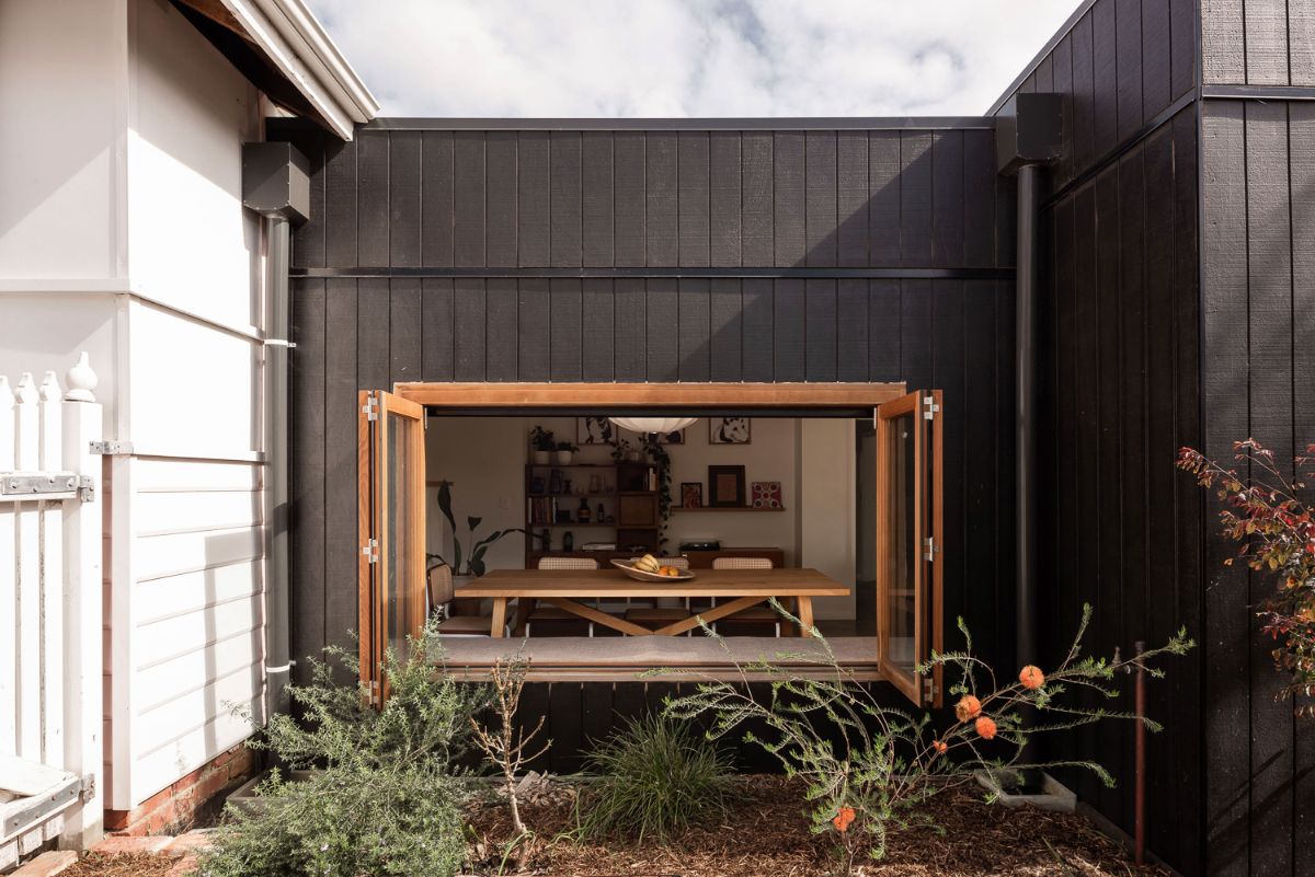 An outdoor view of the eating room with a foldable window and planters filled with a variety of plants.