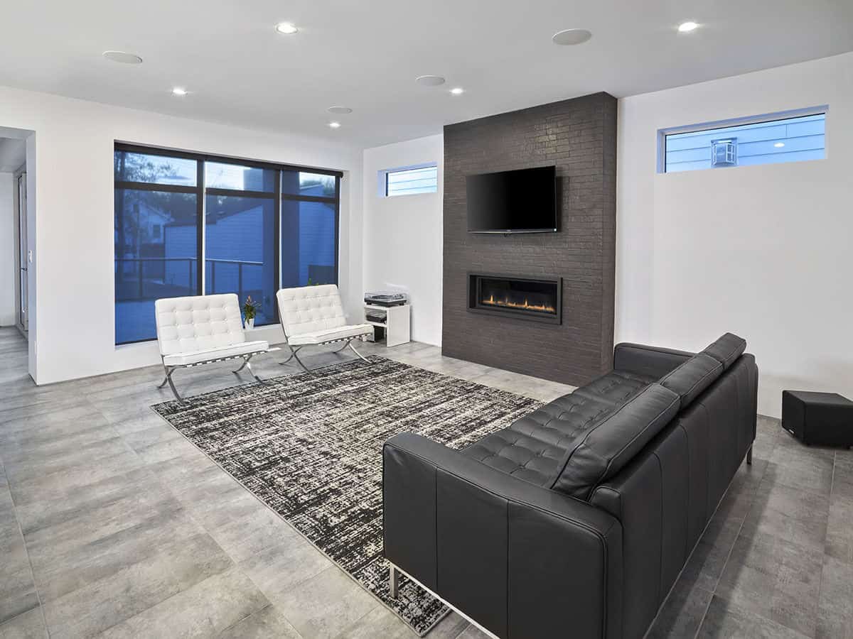 Great room with tufted leather seats and a fireplace topped with a TV.