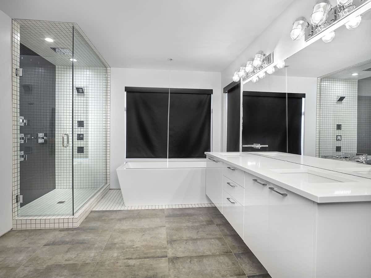 The primary bathroom offers a walk-in shower, a deep soaking tub, and a floating vanity with double sinks and a large frameless mirror.