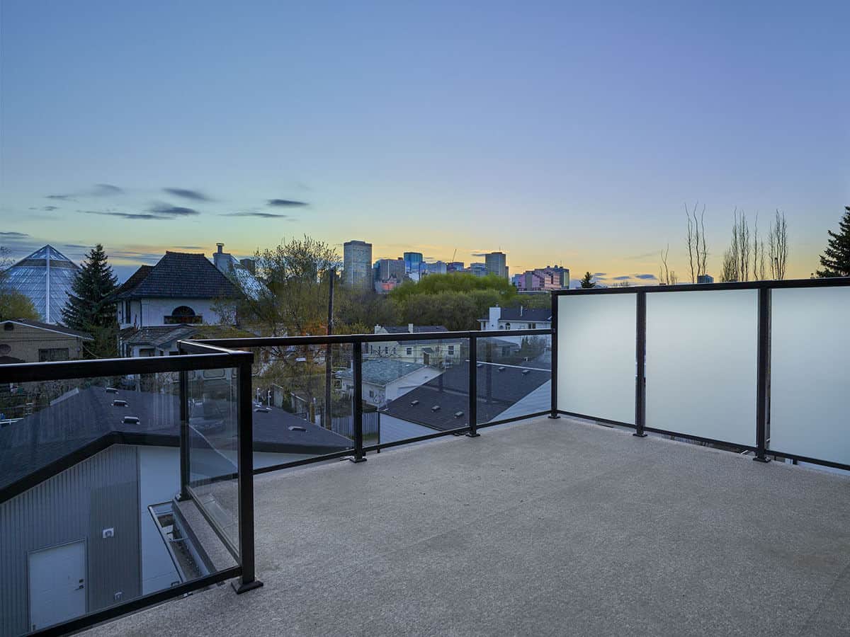 The deck surrounded by glass railings offers expansive views of the neighboring houses.