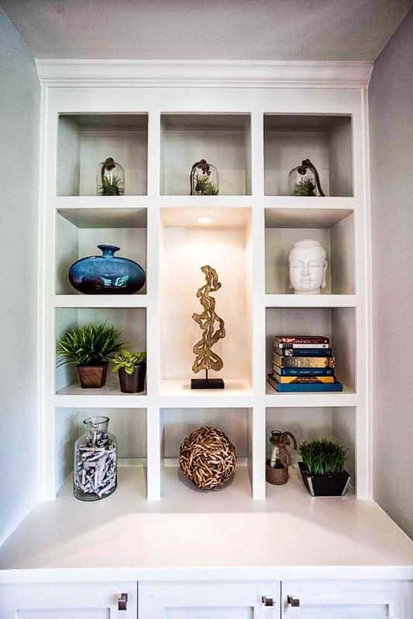 A closer look at the built-in shelves filled with books, potted plants, glass vases, and beautiful sculptures.