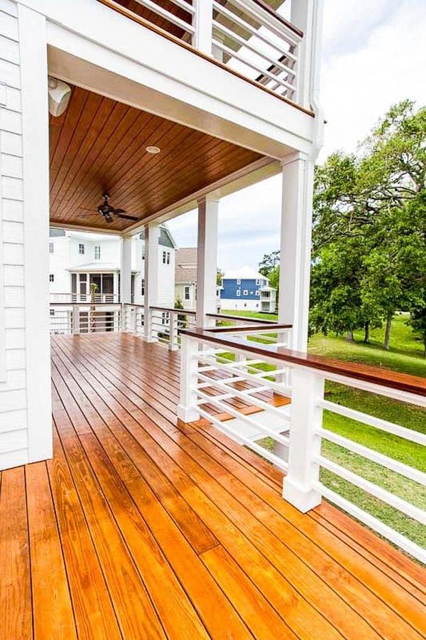 The rear porch is framed with sleek columns and white railings with polished handrails matching with the floor and ceiling.