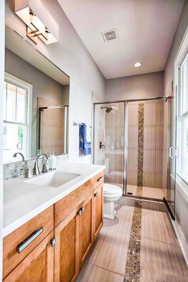 This bathroom offers a sink vanity, a toilet, and a walk-in shower accented with mosaic tiles that extend to the flooring.