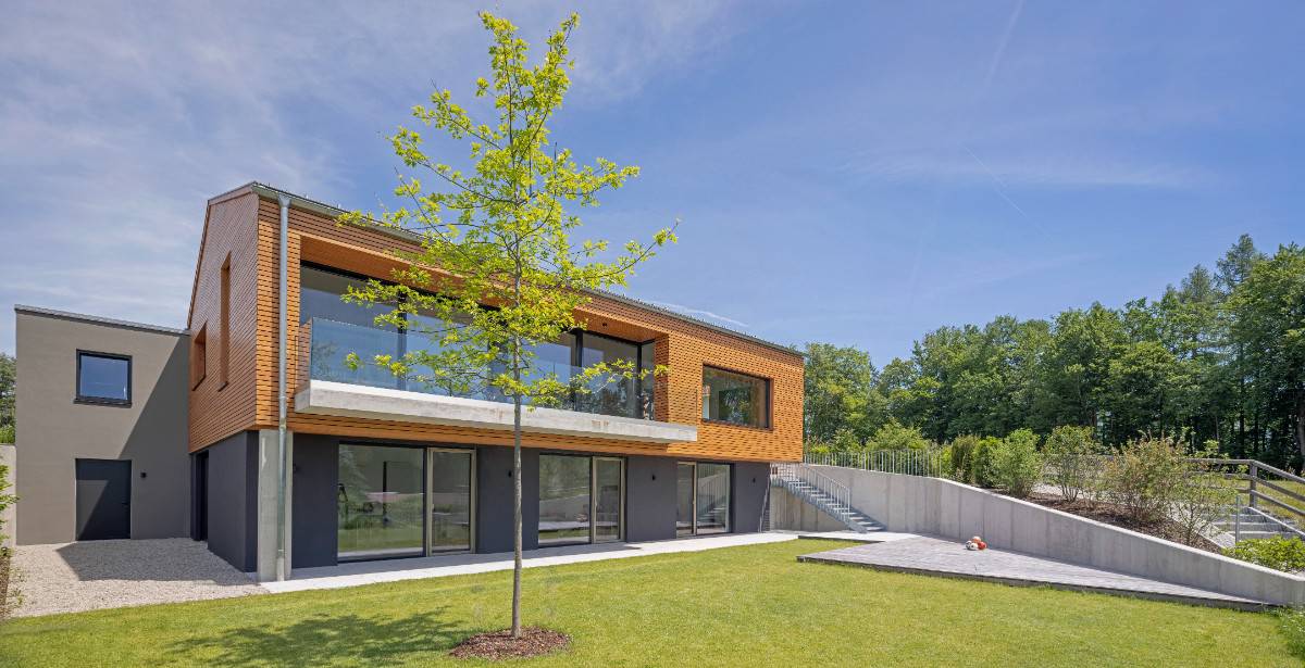 Home's exterior view with gray stucco, warm wood siding, and expansive windows.