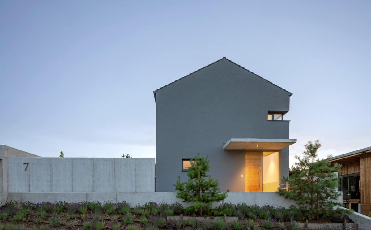 Home's front façade with a gently sloping gable roof and a sleek entrance crowned with a concrete awning.