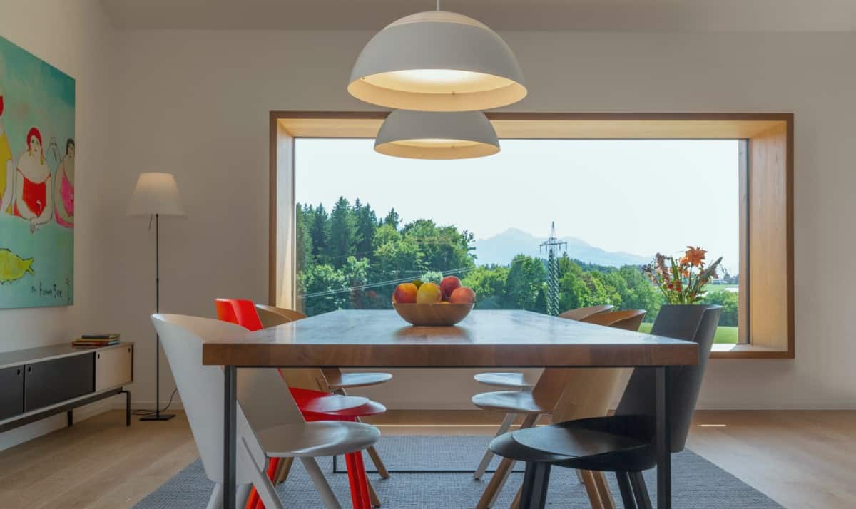 A closer look at the dining area with a wood-top table and multi-colored modern chairs.