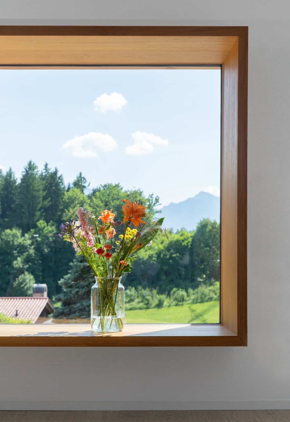 A large picture window captures the serene and lush landscape.