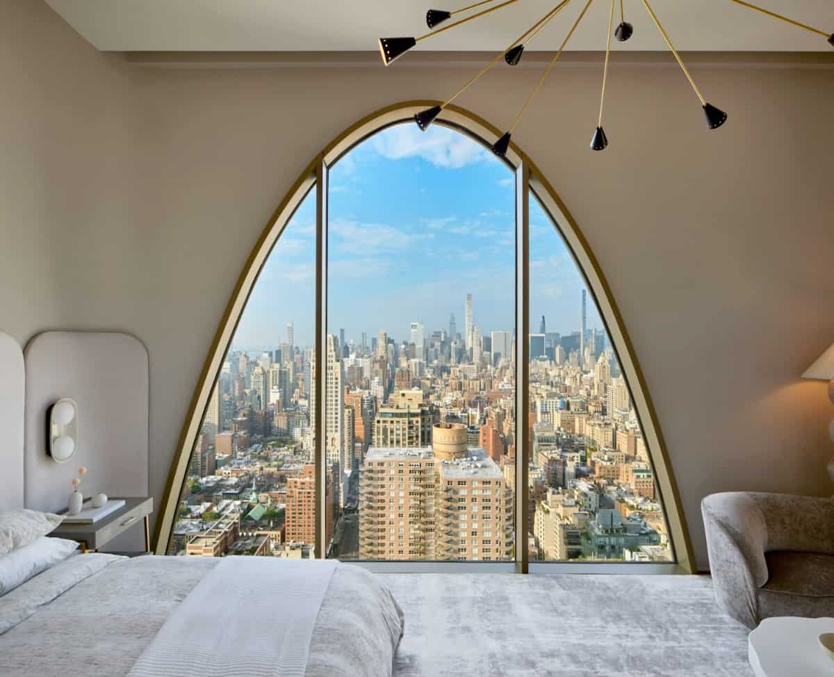 This bedroom offers spectacular city views through a large arched window.