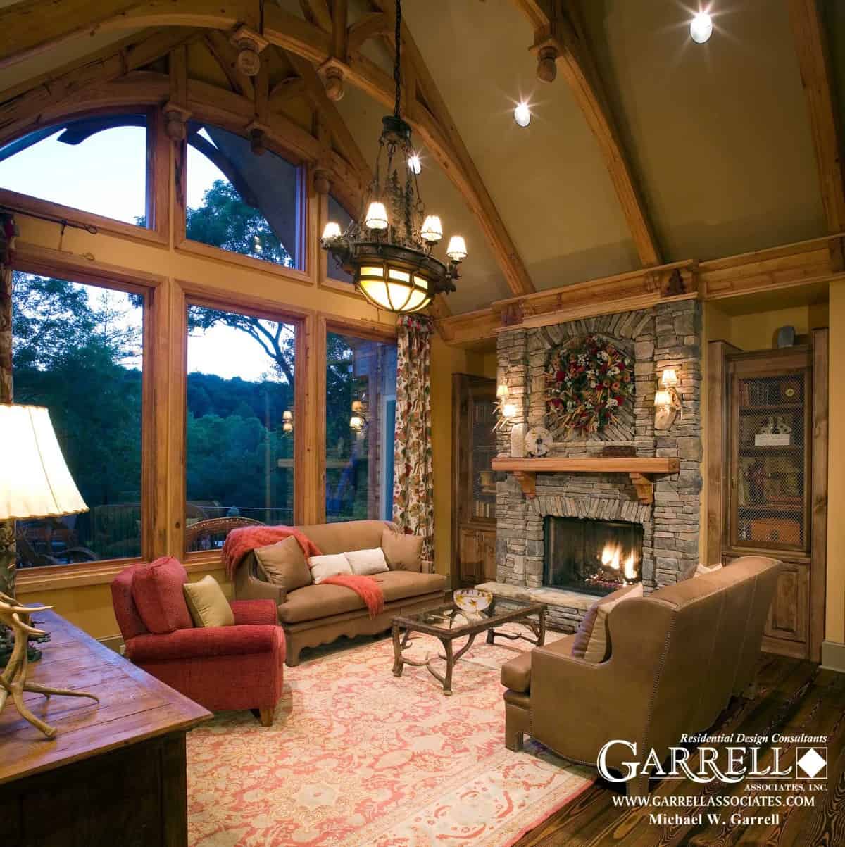 Lodge room with a stone fireplace, massive windows, and a cathedral ceiling framed with exposed trusses.