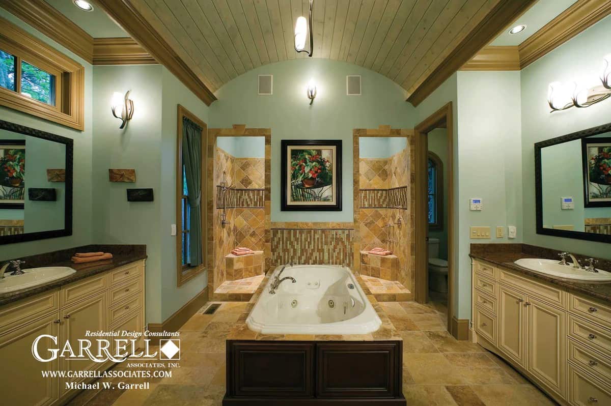 The primary bathroom features his and her sink vanities, a spacious tiled shower, and a deep soaking tub crowned with a barrel-vaulted ceiling.