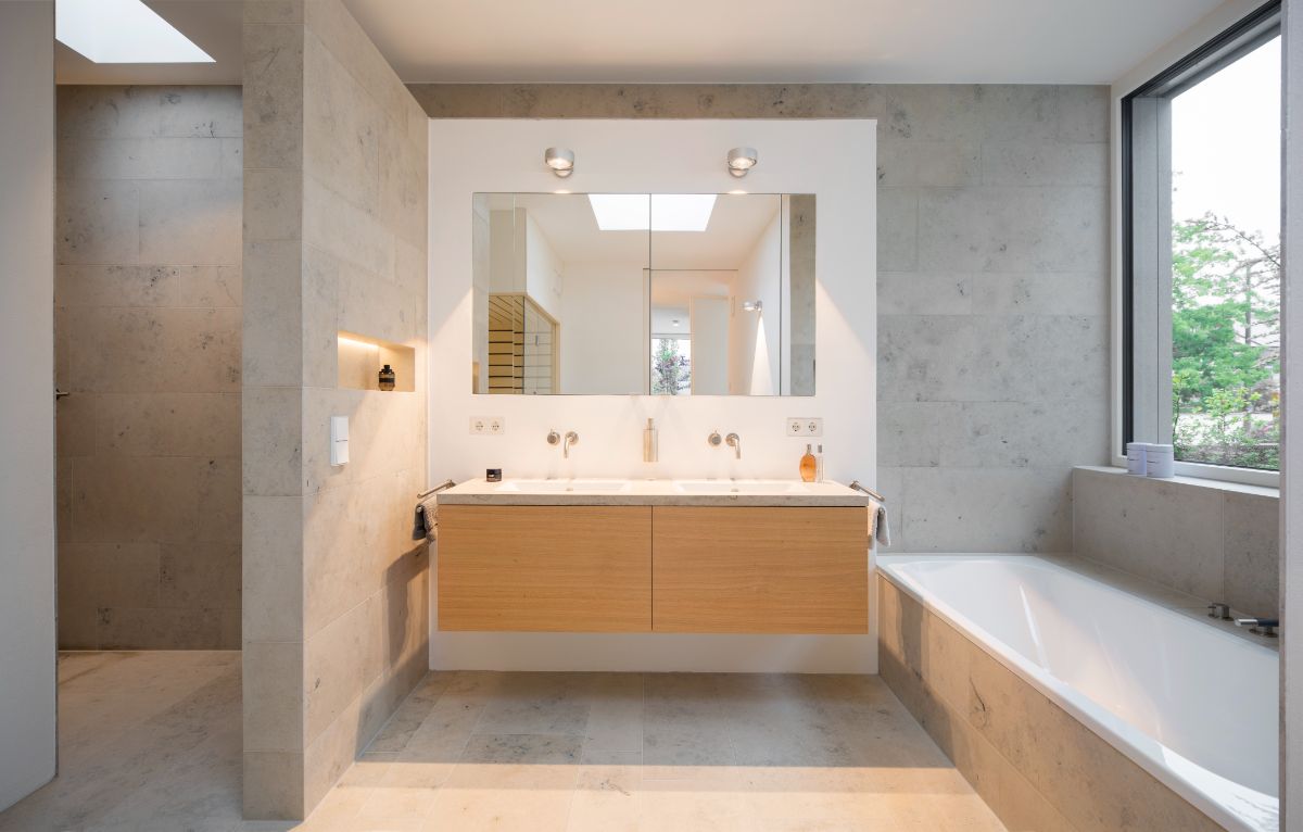 A light-filled bathroom with a built-in deep soaking tub and dual sink undermount on a floating counter beneath a full-width mirror.