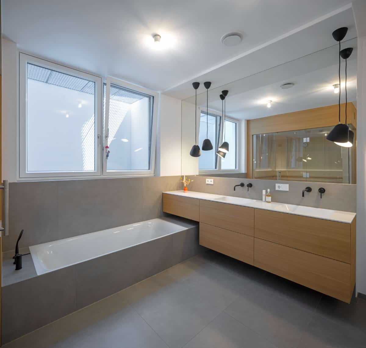 This bathroom features a drop-in bathtub clad in gray tiles that match the flooring.