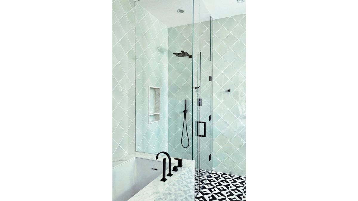 A glass wall divides the shower area, which has tiled walls.