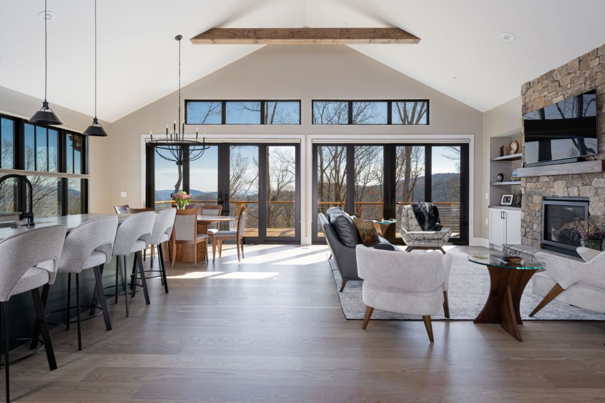 An open and light-filled living, dining, and kitchen layout with high ceilings, expansive windows, and a warm neutral color palette.