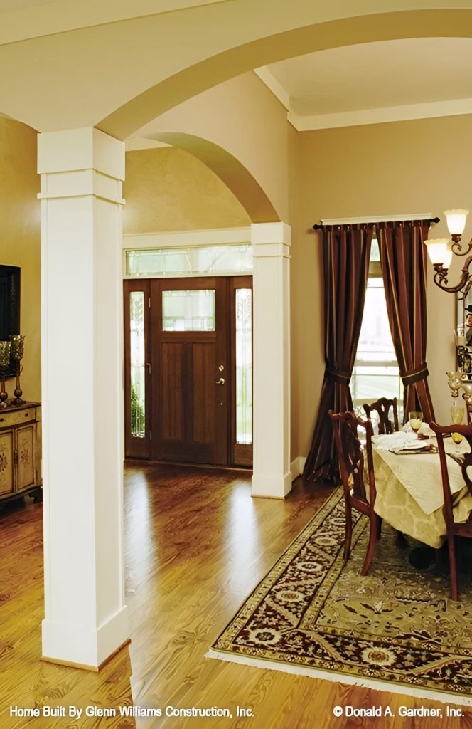 The foyer has a wooden entry door and a large archway leading to the dining room.