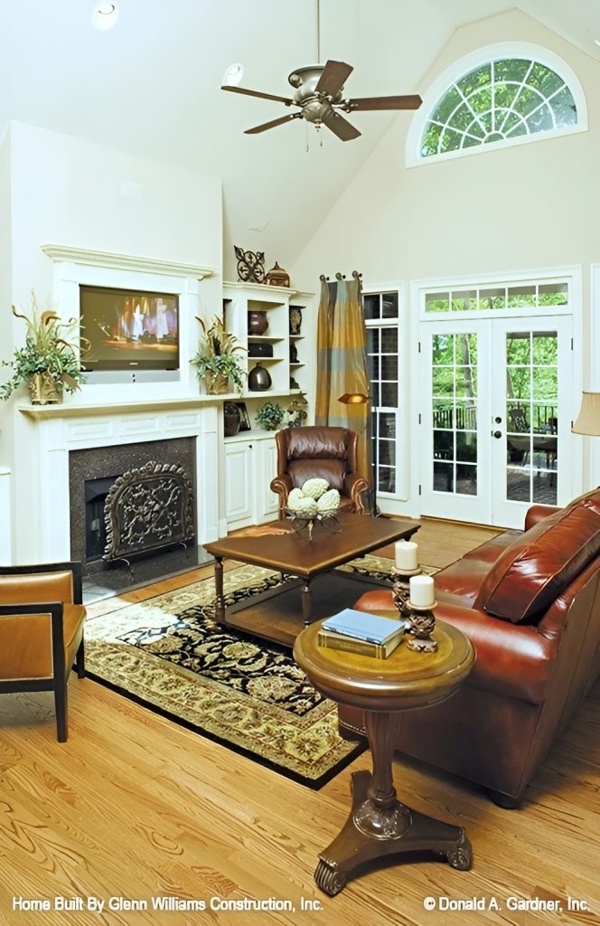 Living room with leather seats, a wooden coffee table, and a fireplace topped with a TV.