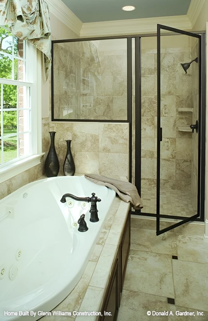 The primary bathroom offers a deep soaking tub and a walk-in shower with wrought iron fixtures.