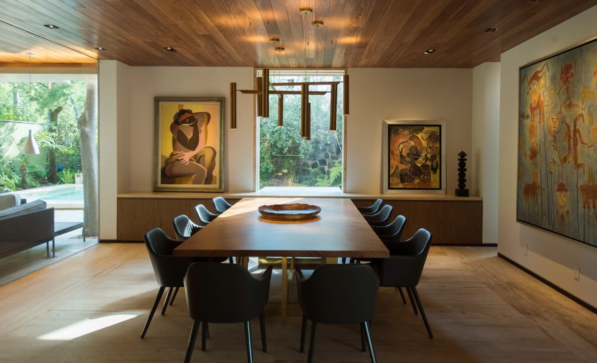 The dining area features natural and artificial lighting, and the artworks display the owner's art collection.