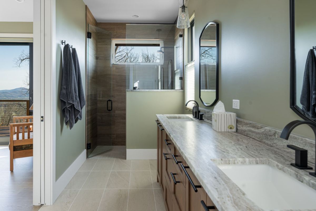 The master bathroom features a glass-enclosed walk-in shower as well as a dual sink undermount on a marble counter. The neutral color scheme from the bedroom is carried over.