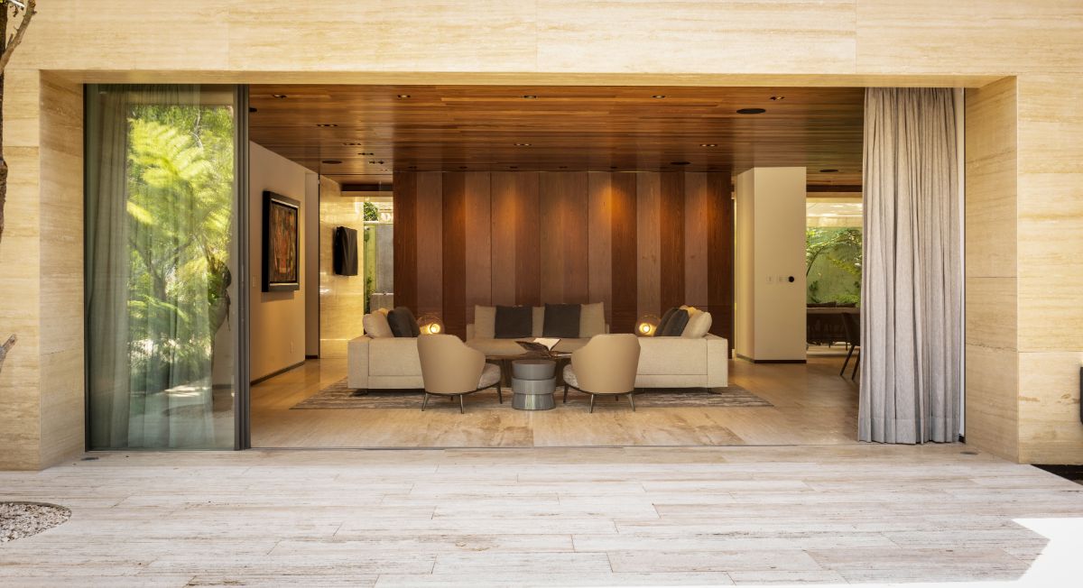 A view of the living area from the outside, with a floor-to-ceiling glass sliding door that may fully open, producing an airy feeling.