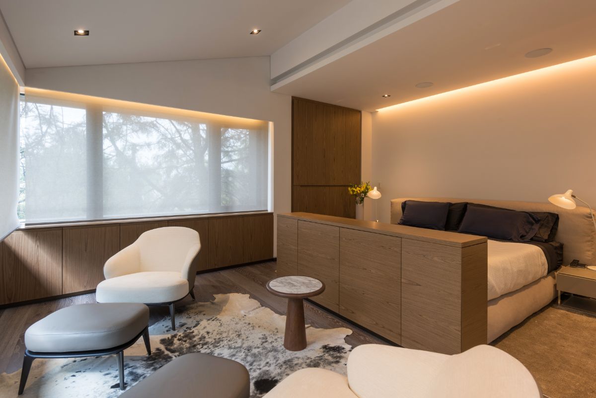 The seating area completes this minimalist bedroom. The huge window is draped with rolling curtains for privacy from the outside.