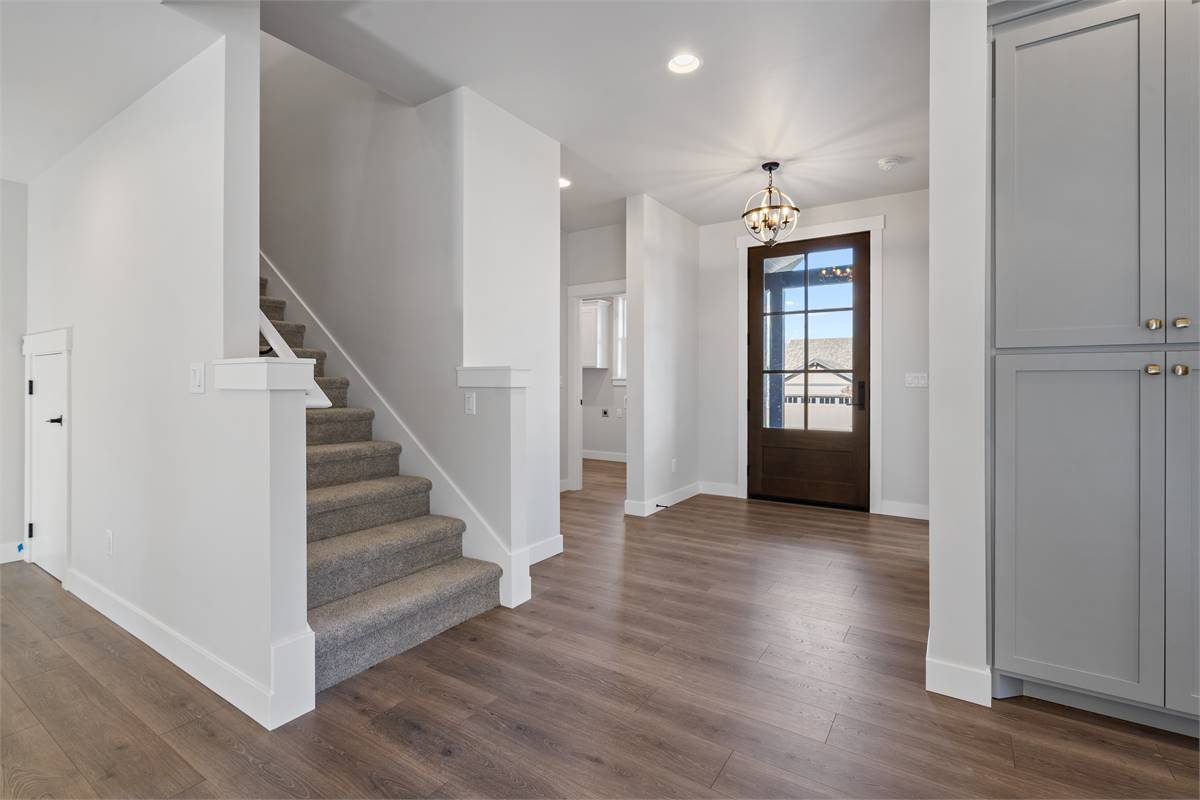 Foyer with a glazed entry door, a spherical chandelier, and a carpeted staircase.