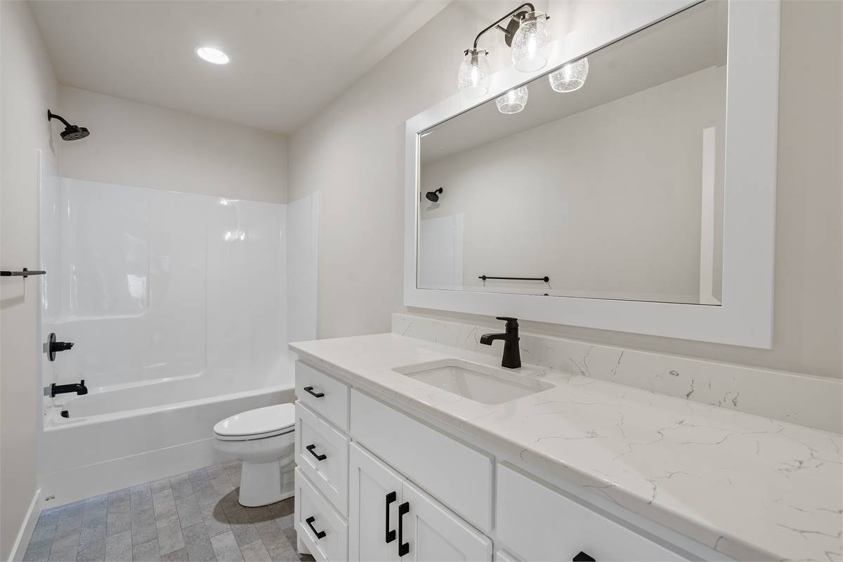 The shared bathroom offers a large sink vanity, a toilet, and a tub and shower combo.