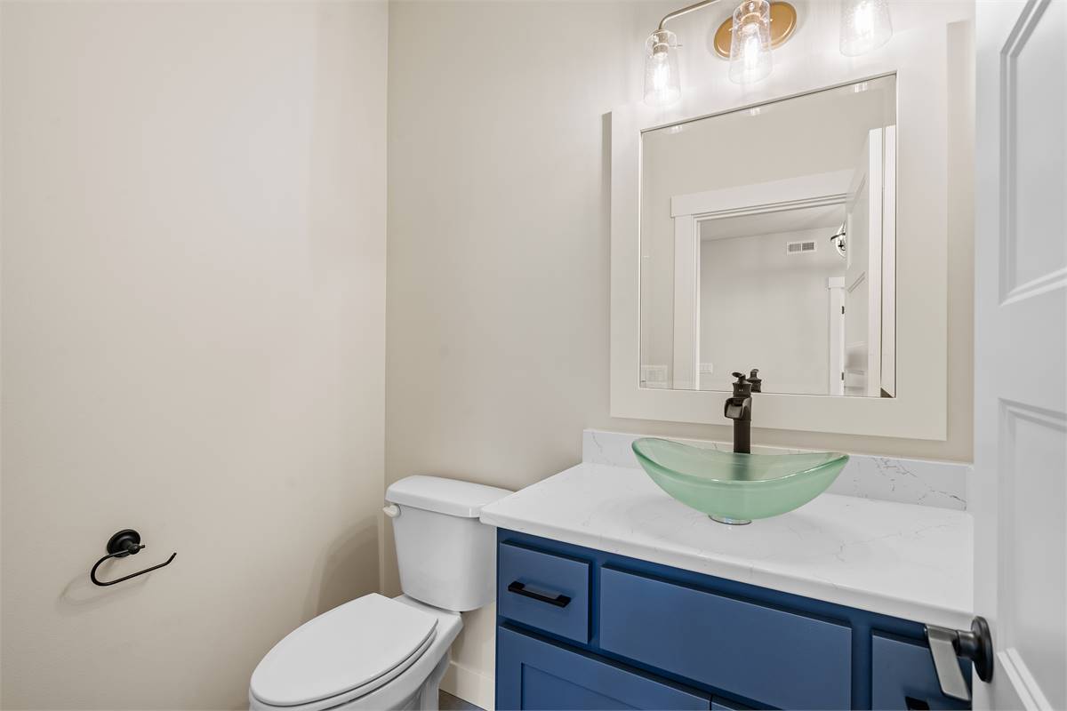 A blue vanity with a glass vessel sink adds a pop of color to the powder room.