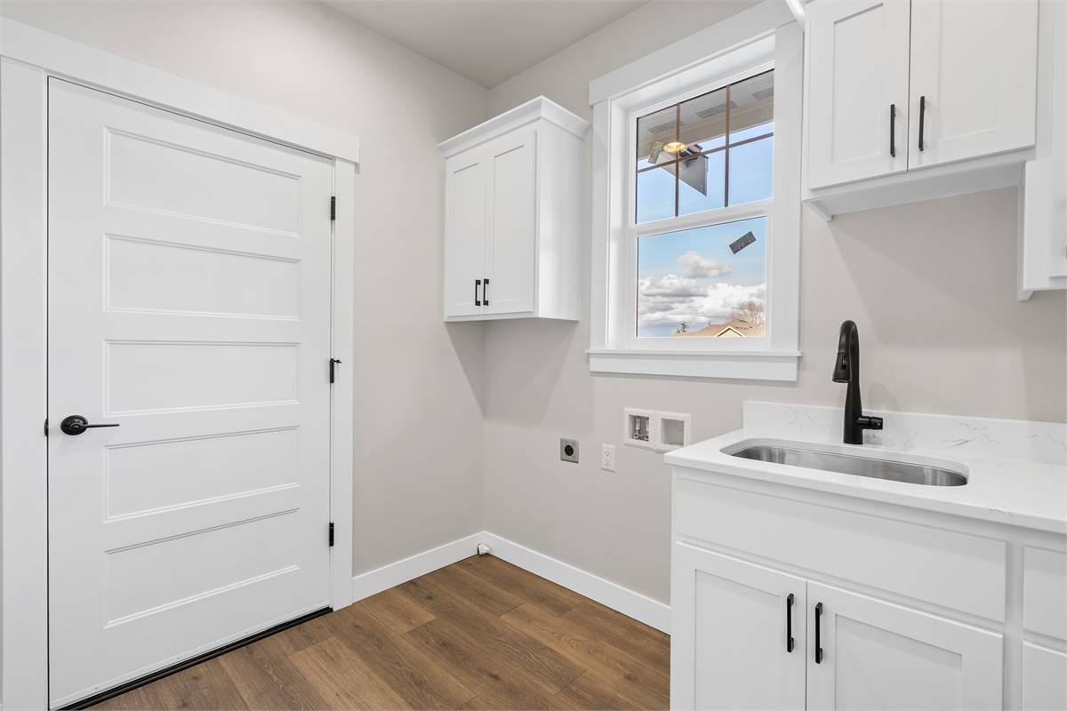 The laundry room is equipped with overhead cabinets and a utility sink.