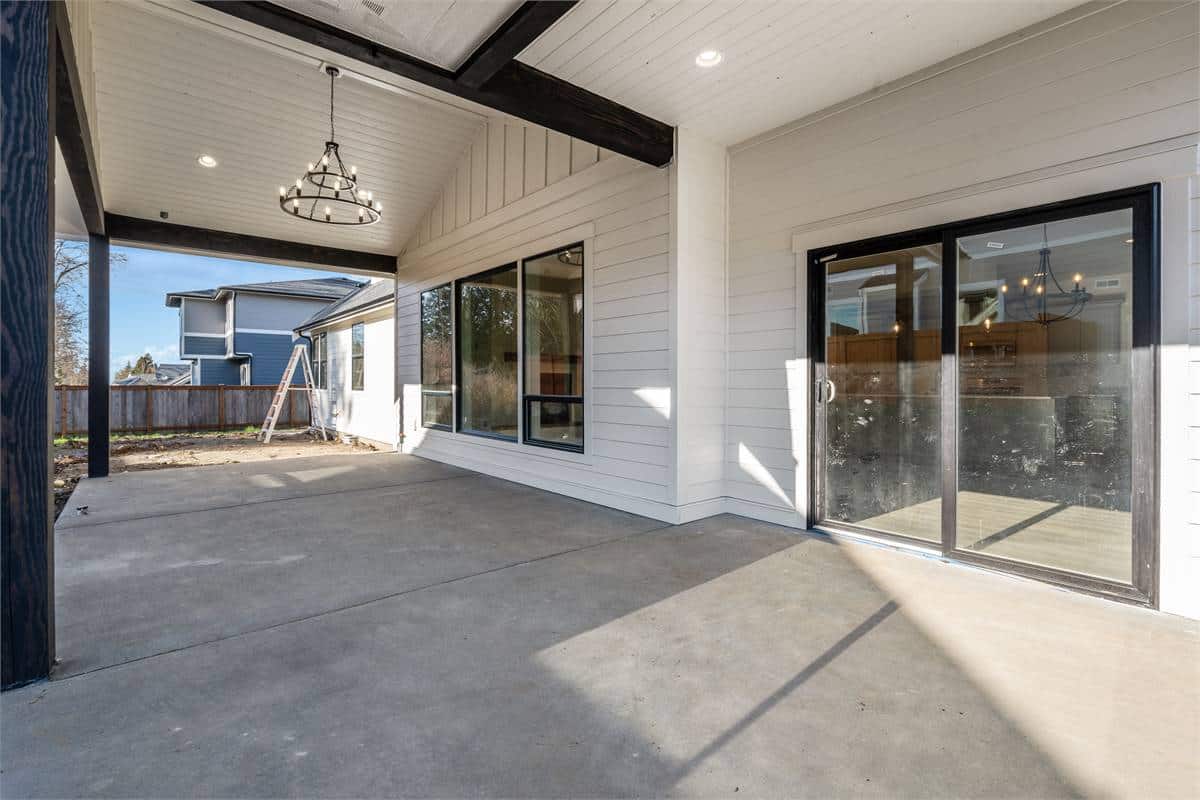 A covered patio with concrete flooring and vaulted ceilings.