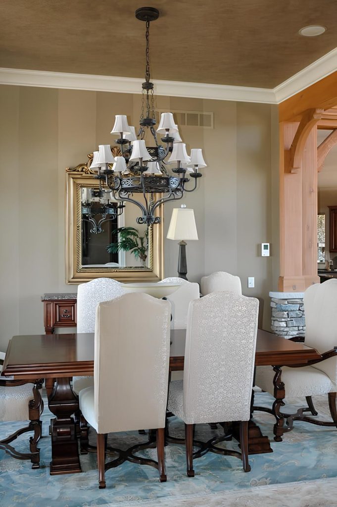 The dining room features an ornate iron chandelier, a wooden dining set, and a matching buffet table topped with a gilded mirror.