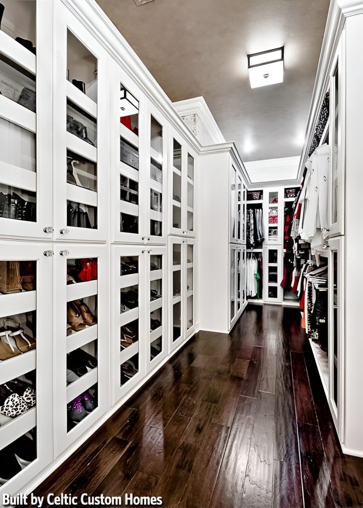 This walk-in closet offers plenty of storage. It has dark hardwood flooring and a regular ceiling mounted with a flush light.