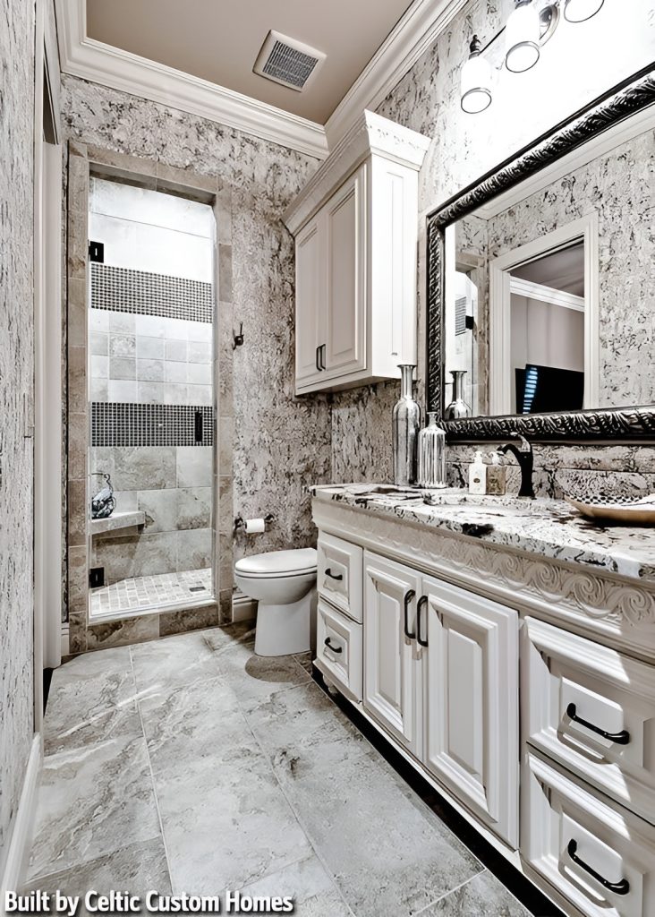 This bathroom is equipped with a large sink vanity, a toilet, and a shower area with a tiled corned seat.