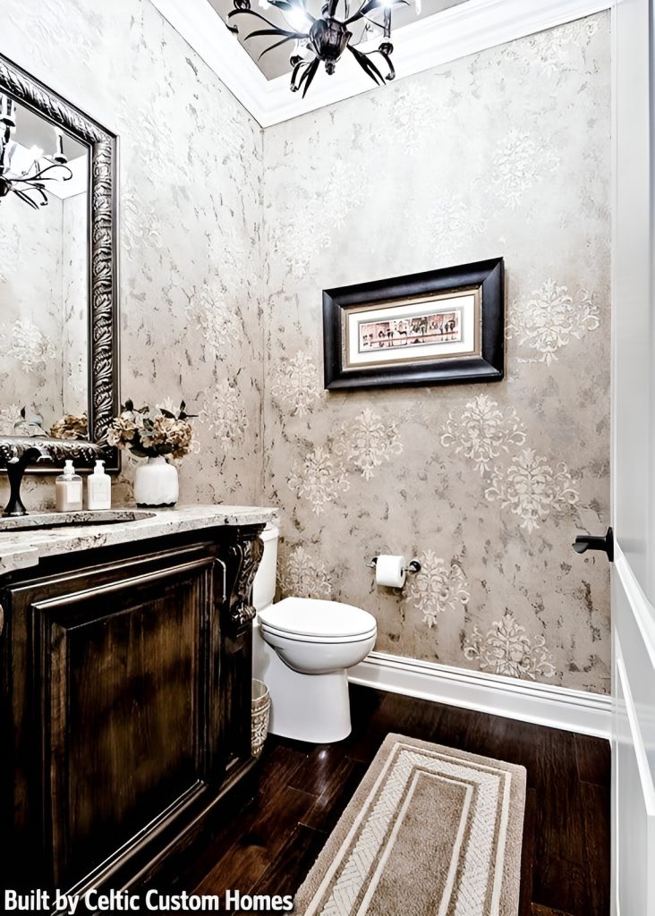 A beautiful wallpaper sets an elegant backdrop to this powder room with a toilet and sink vanity complemented with a bordered runner.