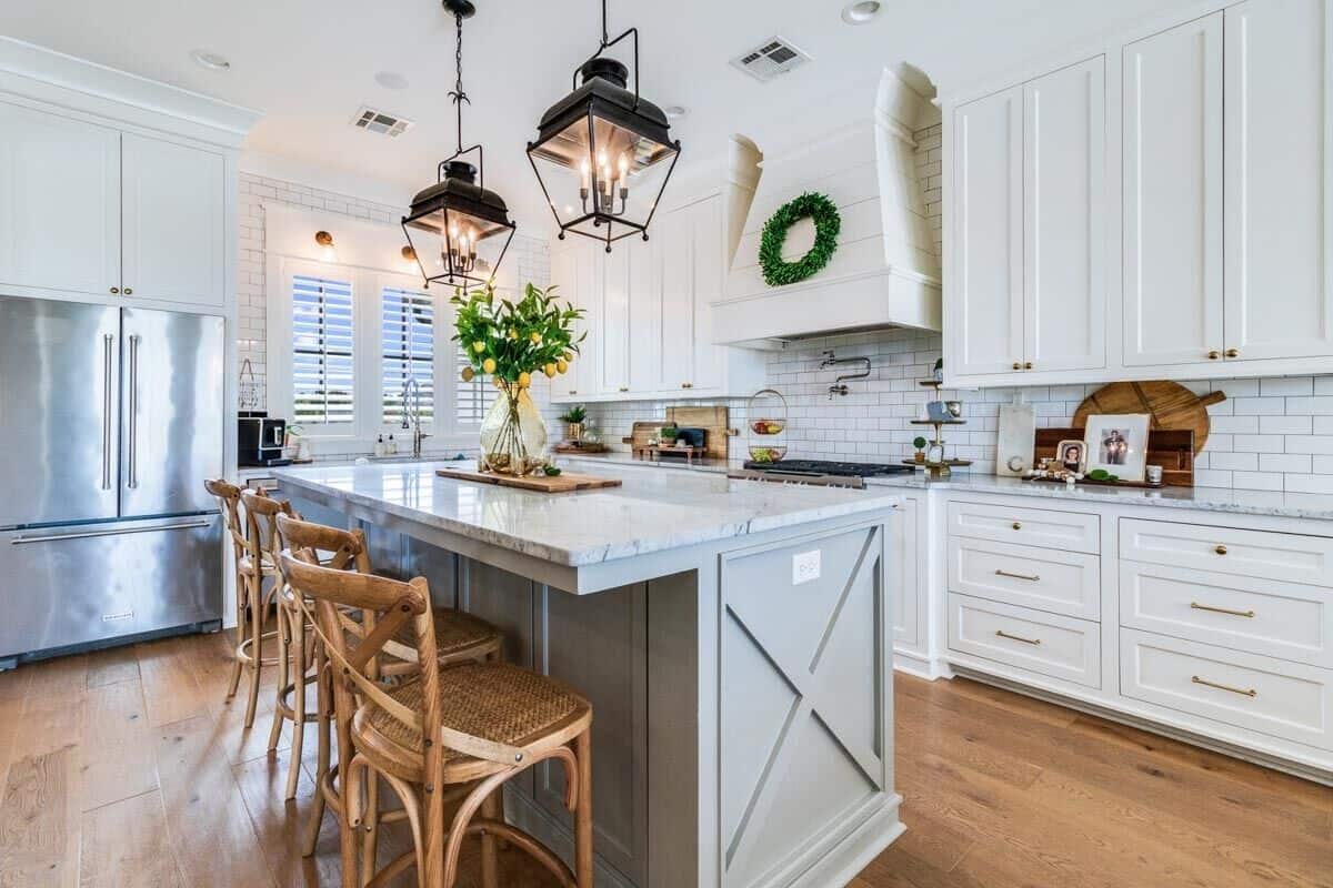 The kitchen has white cabinetry and a breakfast island paired with wooden bar stools.