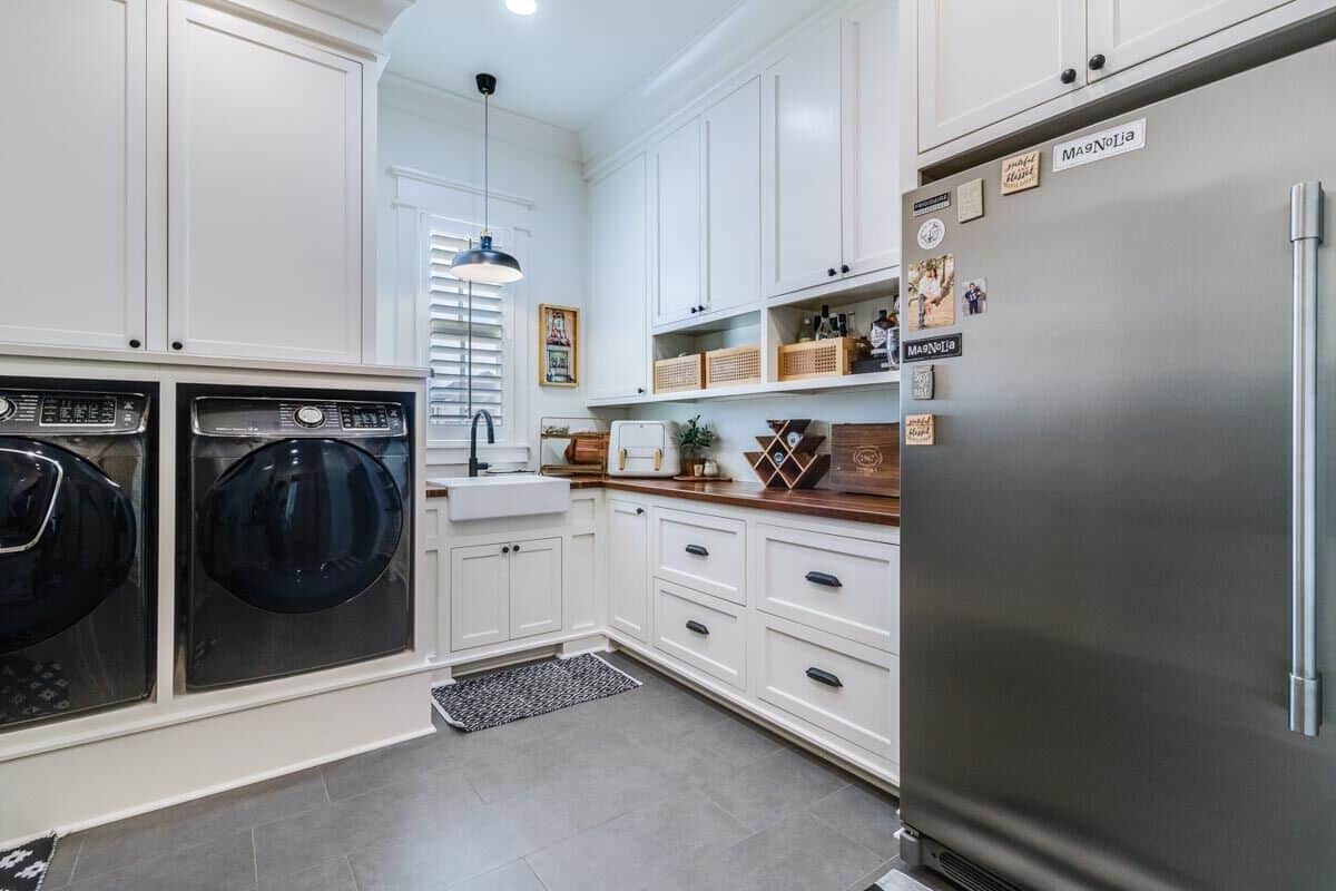 Utility room with laundry appliances, a fridge, a farmhouse sink, and ample storage.