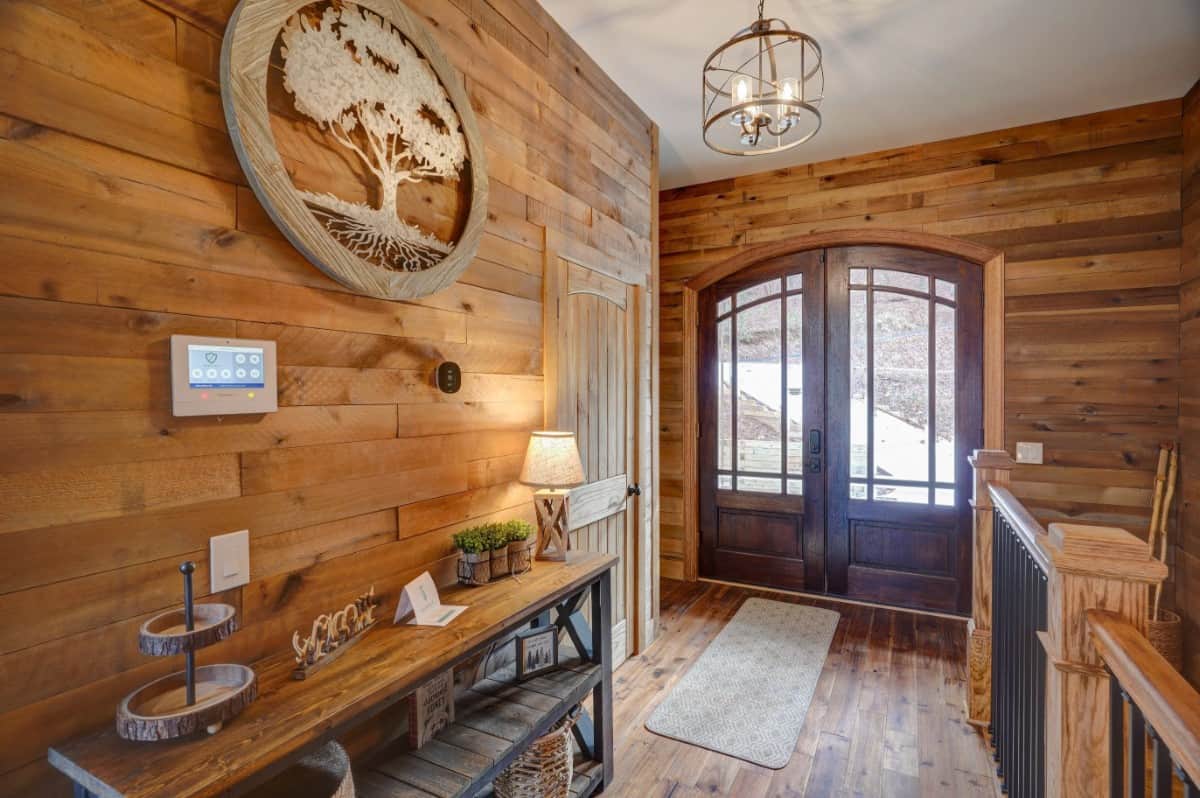 Wood-paneled walls and a matching hardwood floor create a cozy ambiance in the foyer.