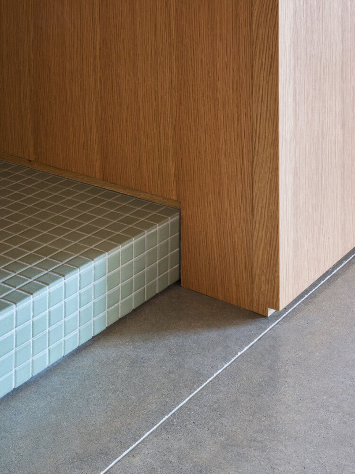 A perfect bathroom color combination. Pastel green for the elevated foor tile, complementing the gray floor tile and wooden cabinets.