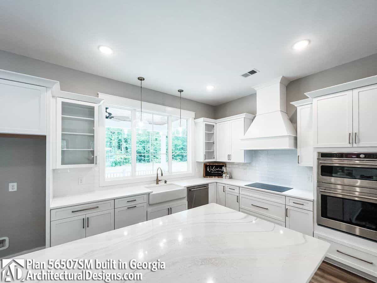 White-framed windows above the farmhouse sink invite natural light into the kitchen.