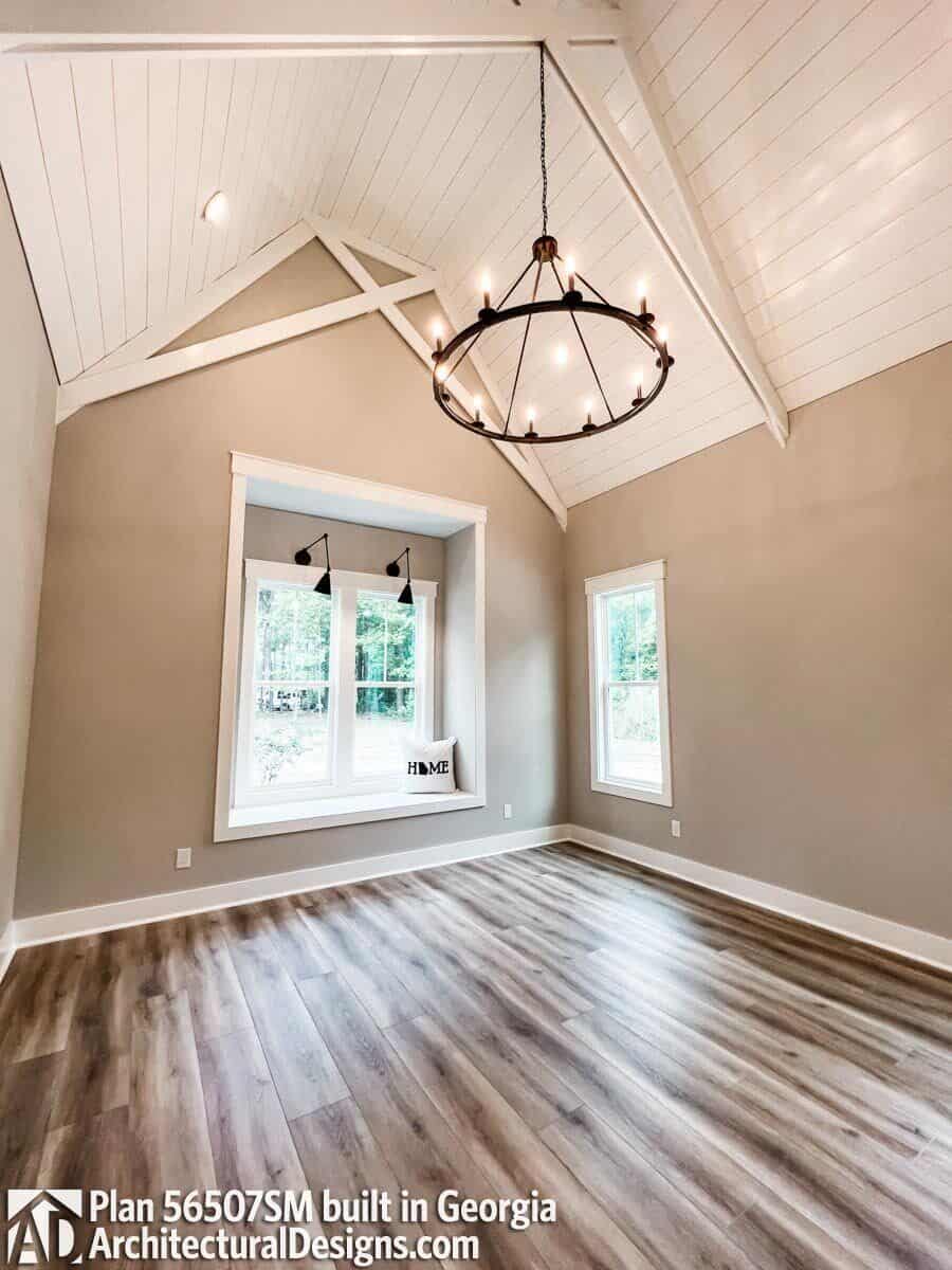 The primary bedroom features a window seat nook and a vaulted ceiling clad in white wood planks.