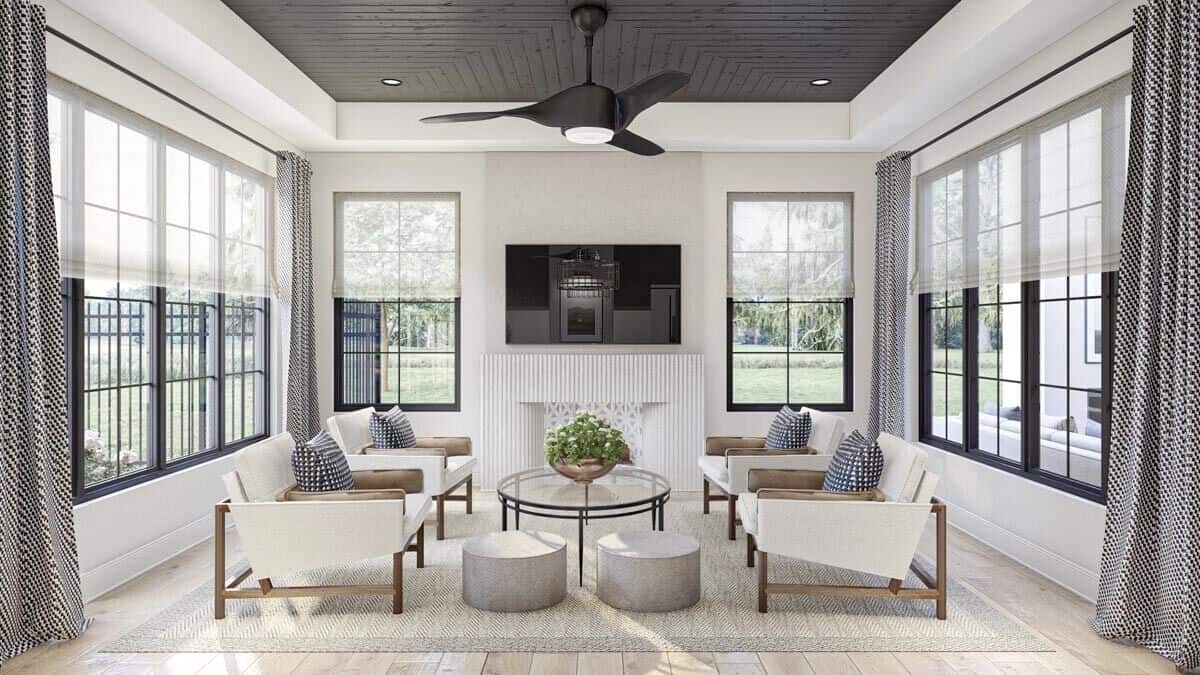 Hearth room with a tray ceiling, a TV above the fireplace, and surrounding windows overlooking the lush backyard.