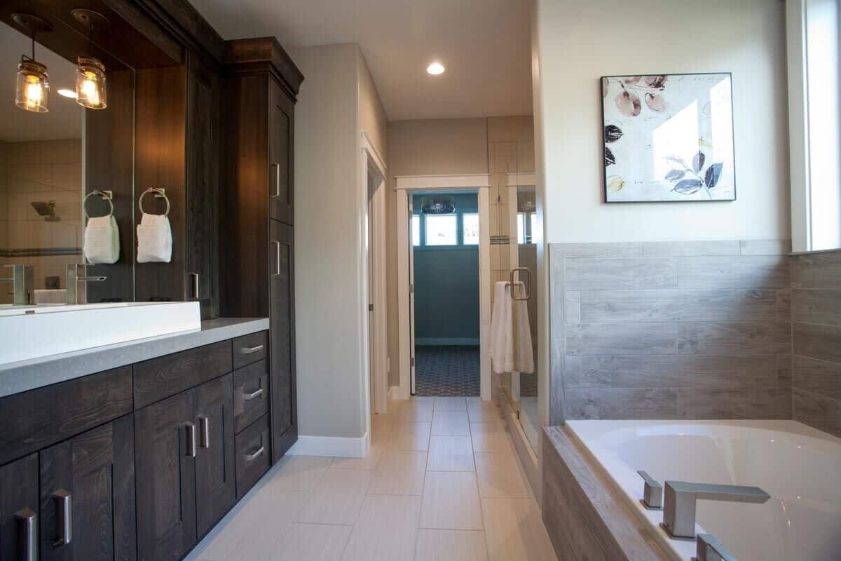 Primary bathroom with a dark wood vanity, a deep soaking tub, and a walk-in closet.