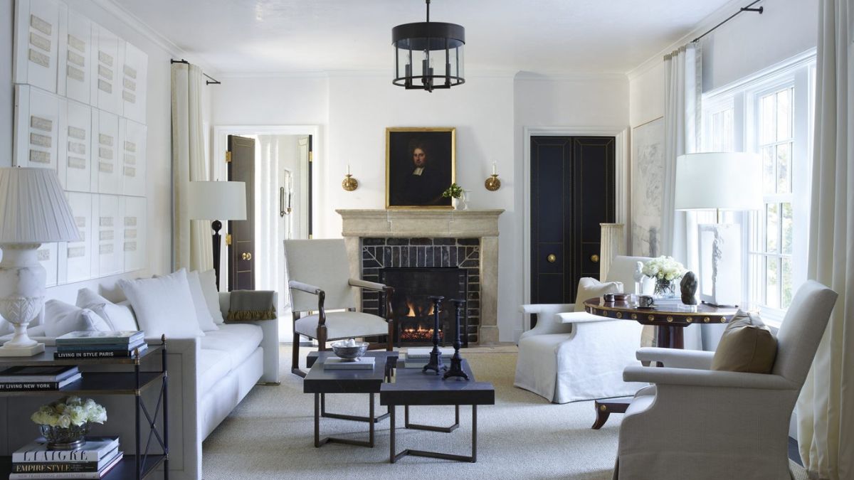 The living space, characterized by a white theme, showcases intricate interior details such as black tables and a striking chandelier.