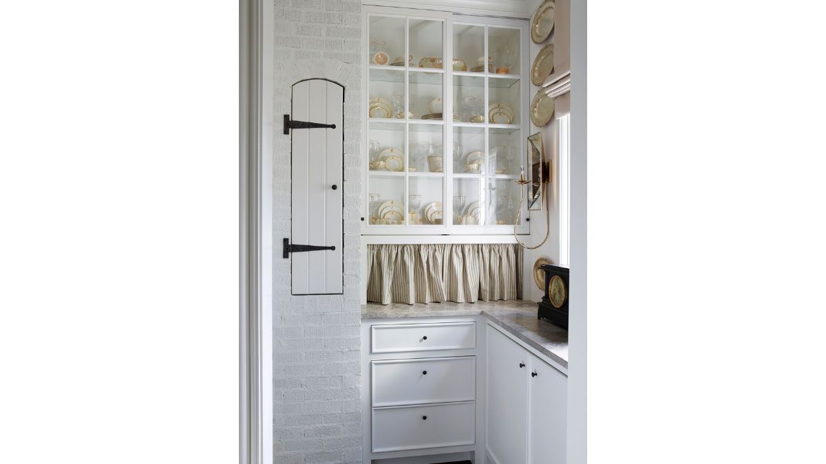 Tea cups and plates are elegantly displayed on white shelves.