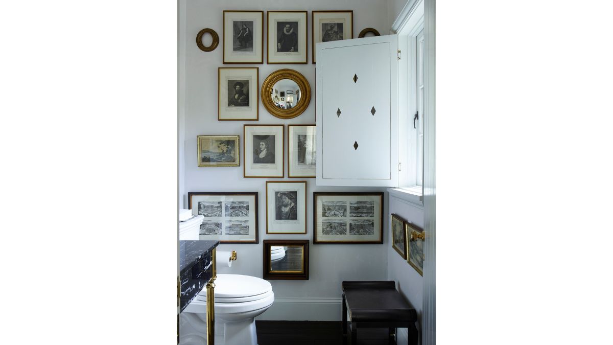 The toilet room features a unique design with frames mounted on the wall, creating a visually interesting display. 