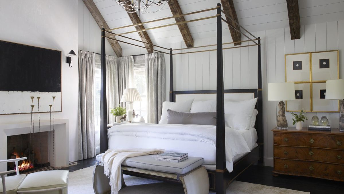 In another bedroom of the house, the bed is showcased with attached woods extending from the corners and connecting to the ceiling, along with a firepit.