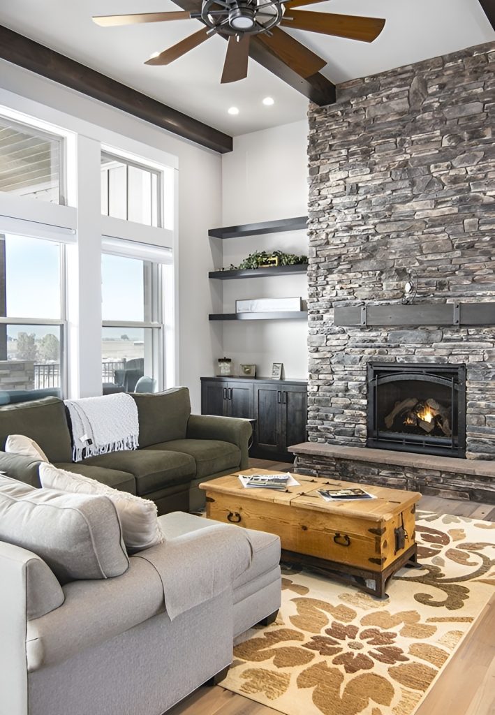 The living room has clerestory windows, a stone fireplace, and comfy sectionals paired with a wooden chest coffee table.