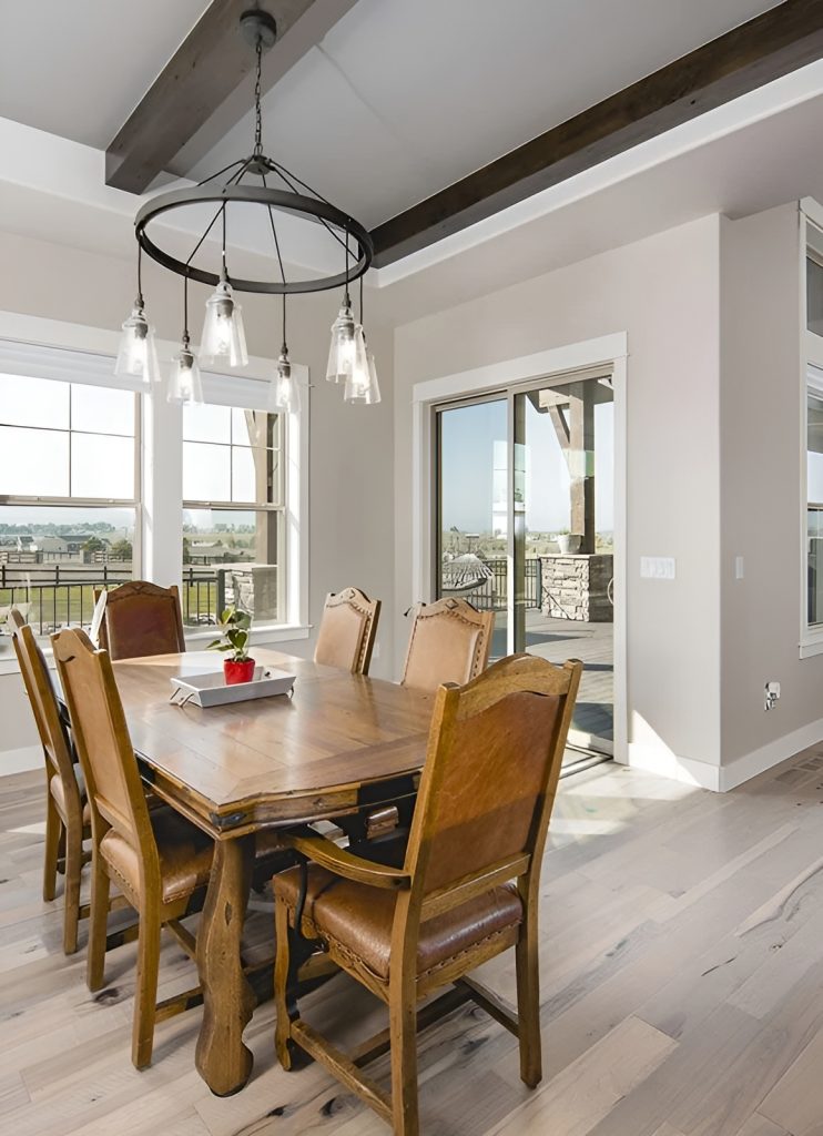 Dining area with a wooden dining set and a round chandelier that hangs from the beamed ceiling.