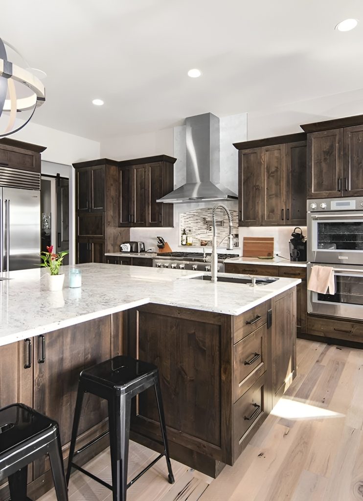 The kitchen is equipped with marble countertops, stainless steel appliances, wooden cabinetry, and a sink fitted on the island.